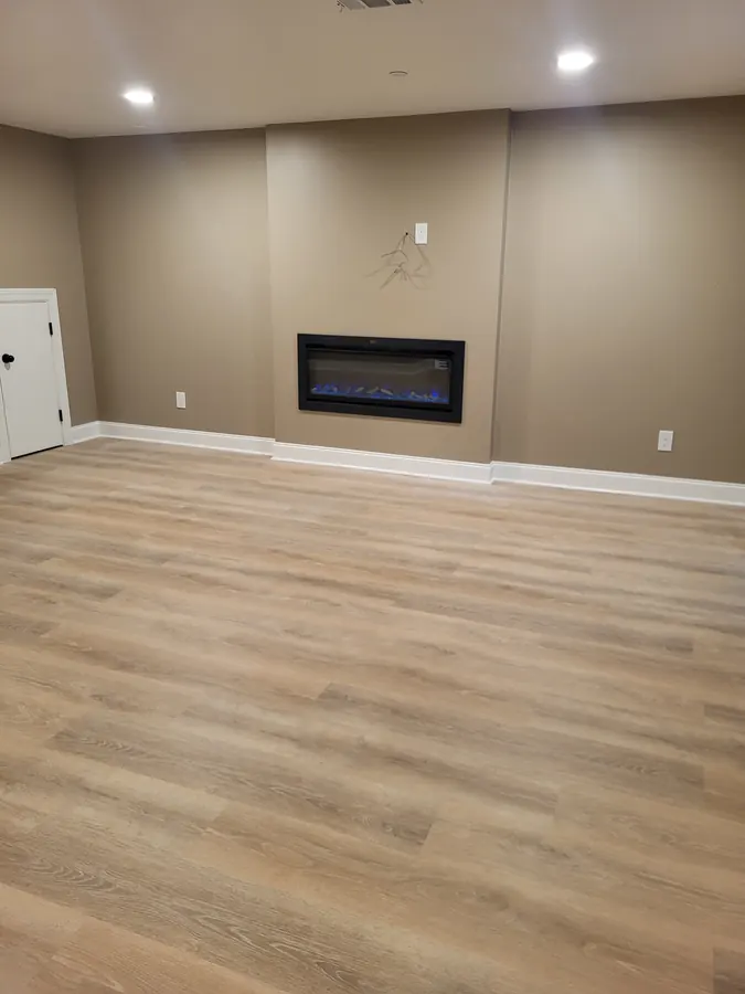 Finished basement fireplace wall with recessed lighting and light flooring