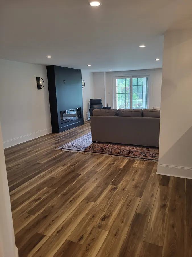 Finished basement lounge with fireplace wall, sofa, and walkout doors